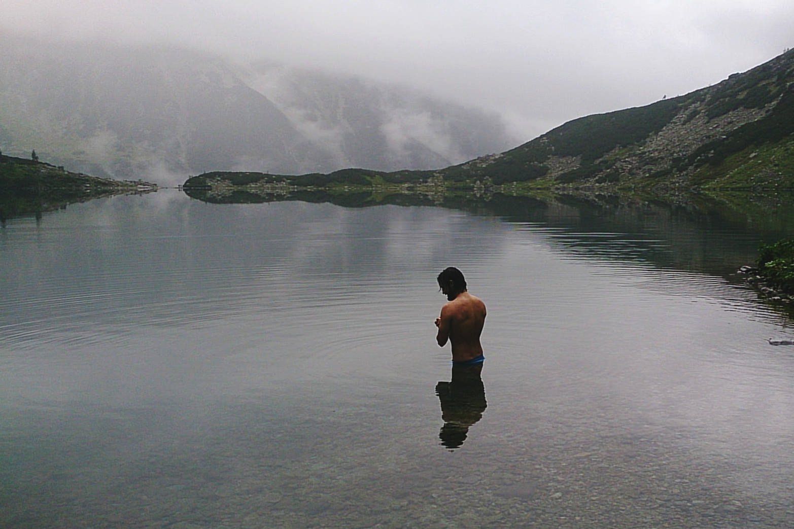 A Man Getting Ready To Take A Dip In The Mountain Lake