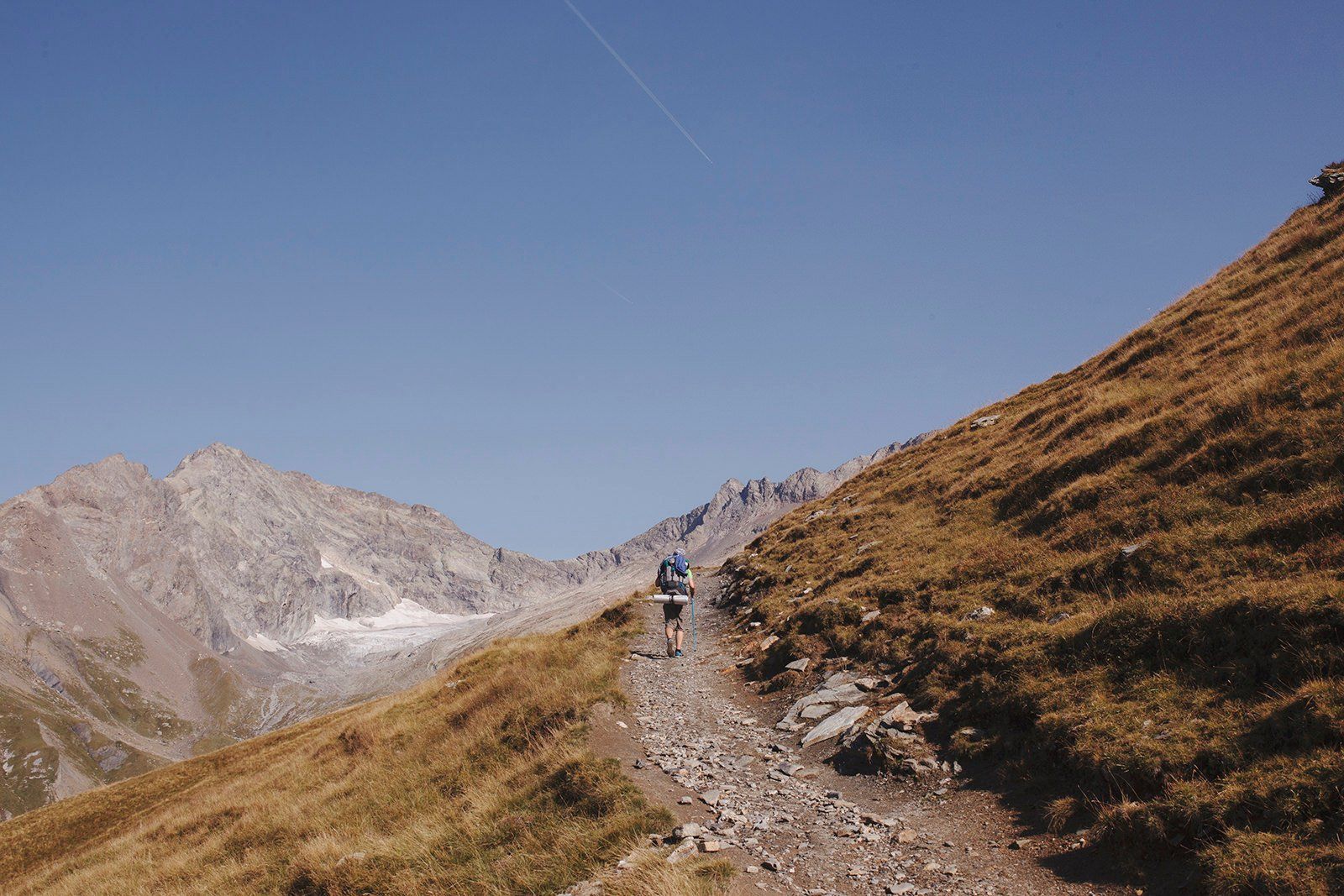 A Man Hiking Towards The Mountain Pass