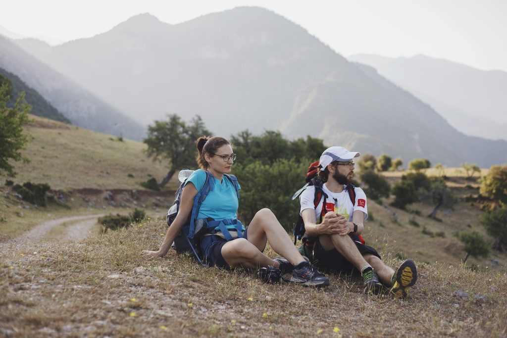 A couple sitting on a hill with mountains in the background