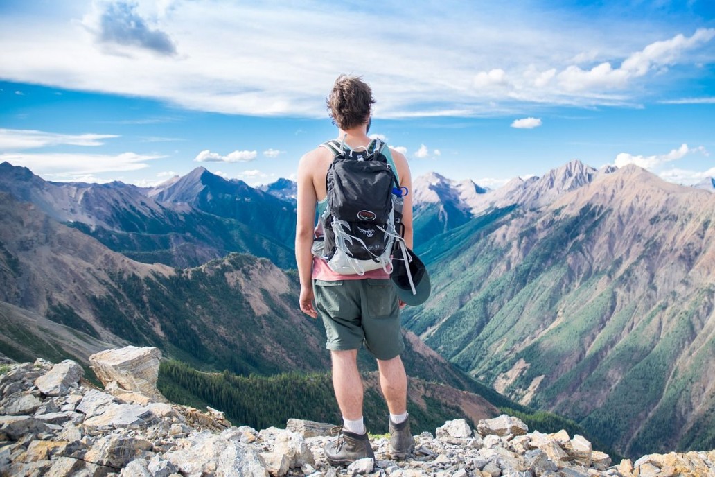 A Guy Near A Cliff Looking Over The Mountains